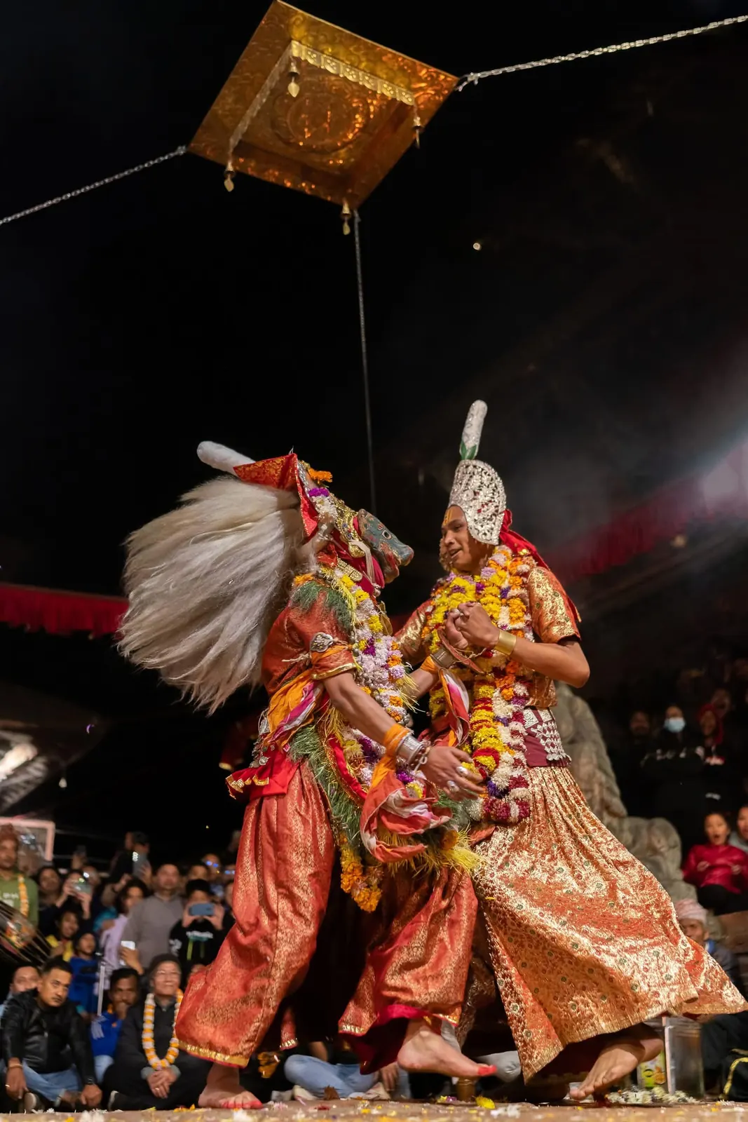 Two dancers in crowns and long white hair dance under the canopy